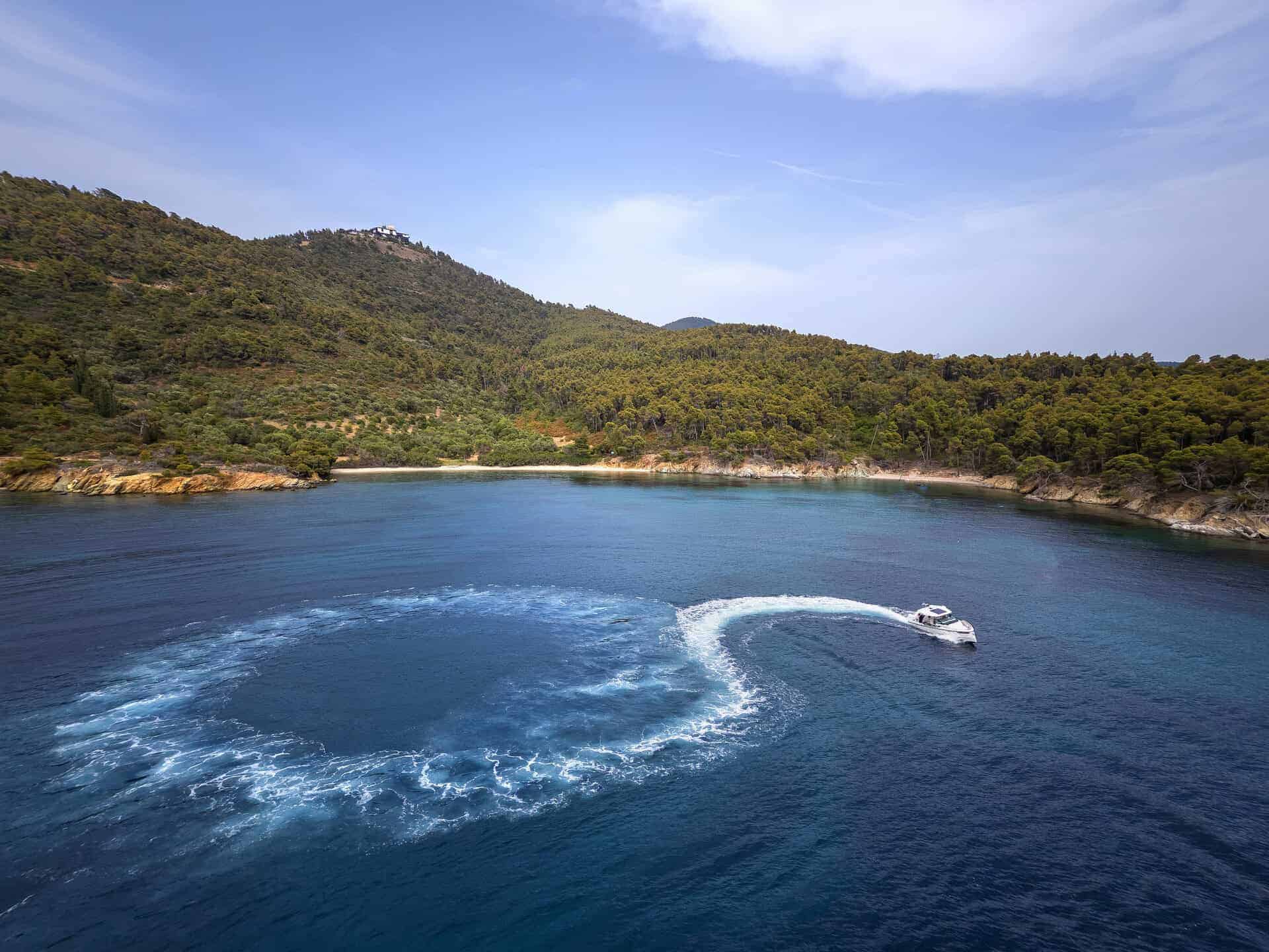 Aerial view of the Saxdor 320 GTO creating a circular wake pattern in a secluded bay surrounded by lush greenery and clear blue waters
