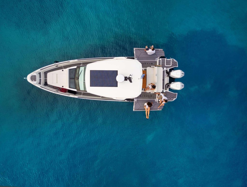 A top-down view of the Saxdor 320 GTO 'Paralos' yacht anchored in the clear blue waters of Halkidiki, with guests relaxing on the deck