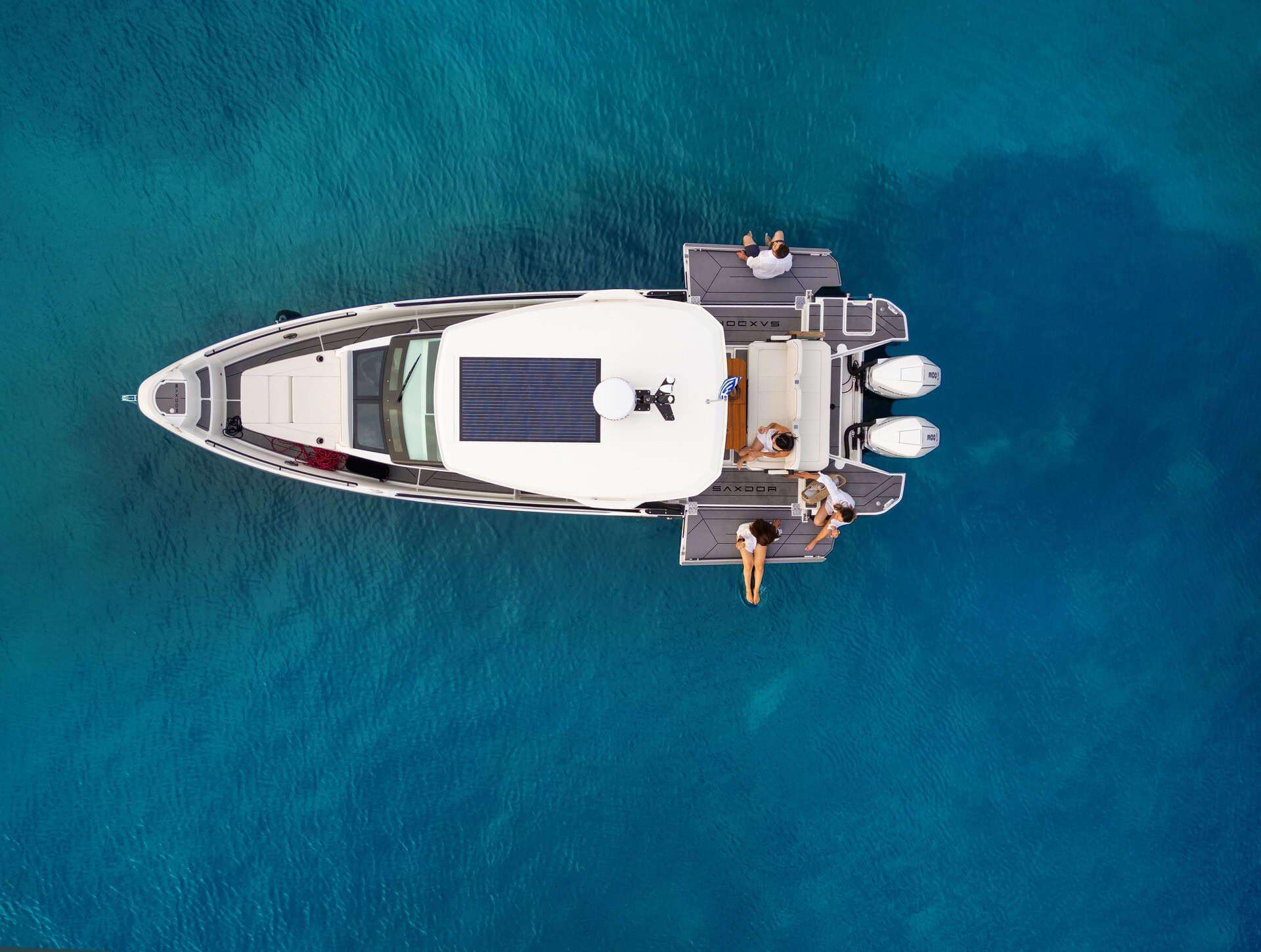 A top-down view of the Saxdor 320 GTO 'Paralos' yacht anchored in the clear blue waters of Halkidiki, with guests relaxing on the deck