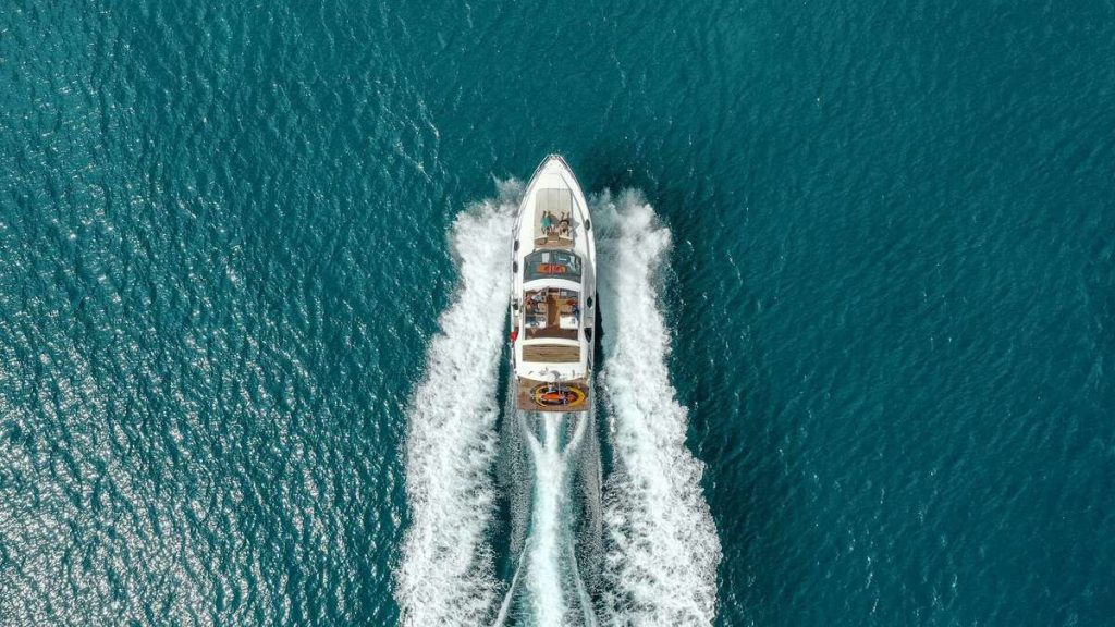 A top-down view of a yacht speeding through the vibrant blue waters of Halkidiki