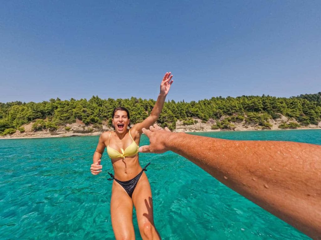 smiling woman getting pushed into the sea from boat