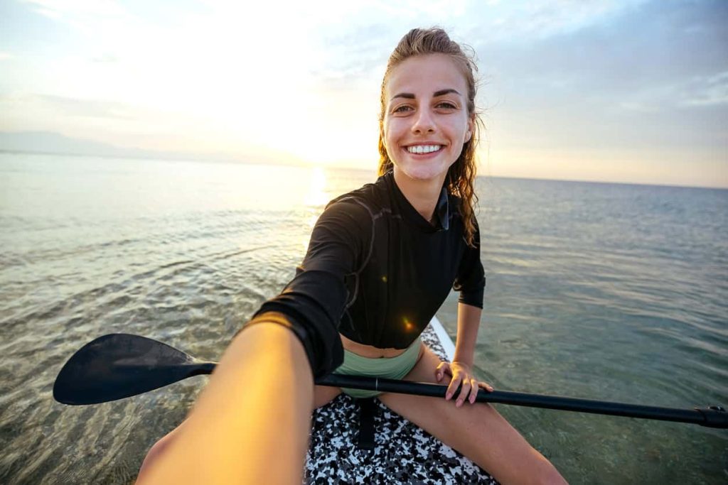 Smiling woman on stand up paddle board at sunset in Halkidiki