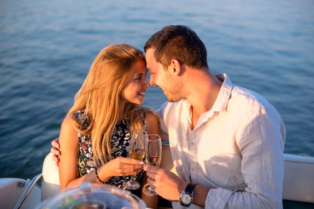 A romantic couple enjoying a sunset toast on a yacht, celebrating their perfect getaway with champagne and a beautiful sea backdrop