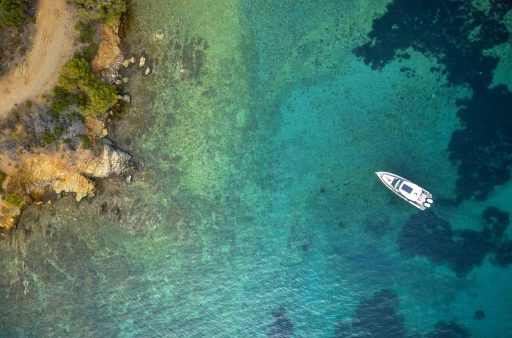 A top-down aerial view of the Saxdor 320 GTO 'Paralos' yacht anchored in the clear, turquoise waters of a serene cove in Halkidiki