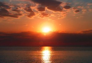 A breathtaking sunset over the calm waters of Halkidiki, with vibrant orange and red hues reflecting off the sea