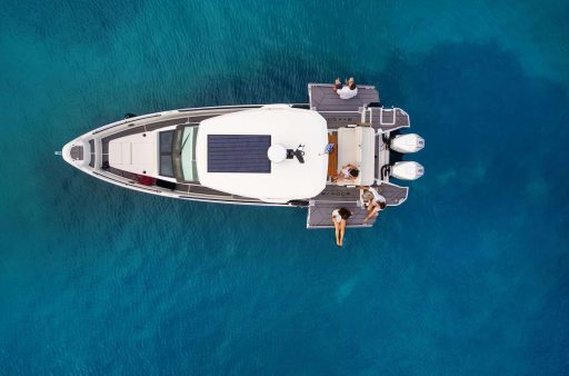 A top-down view of the Saxdor 320 GTO 'Paralos' yacht anchored in the clear blue waters of Halkidiki, with guests relaxing on the deck